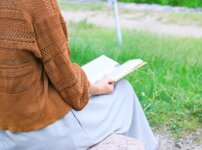 公園のベンチで本を読む女性