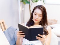部屋で洋書を読む女性