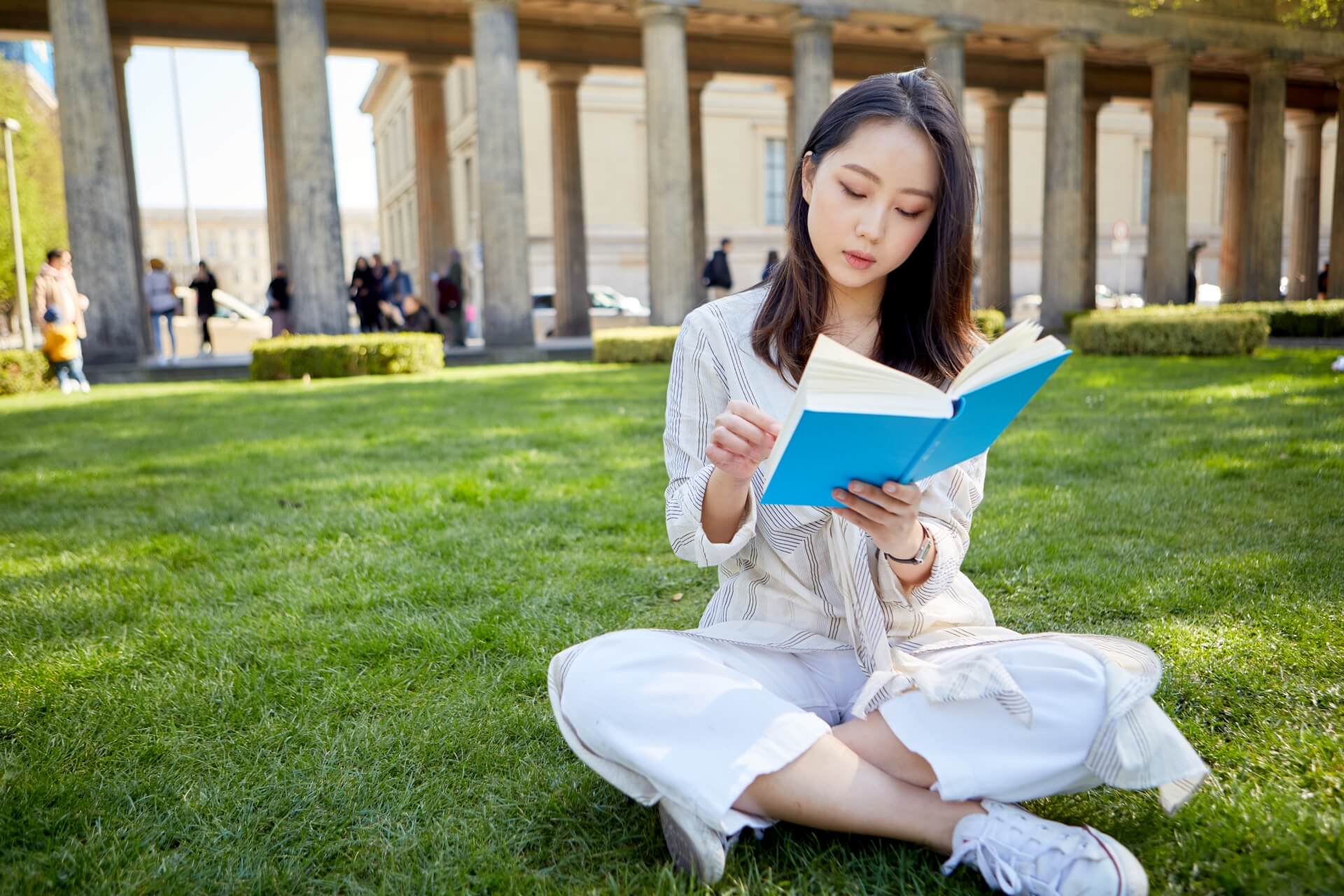 芝生の上で本を読むアジア人女性2