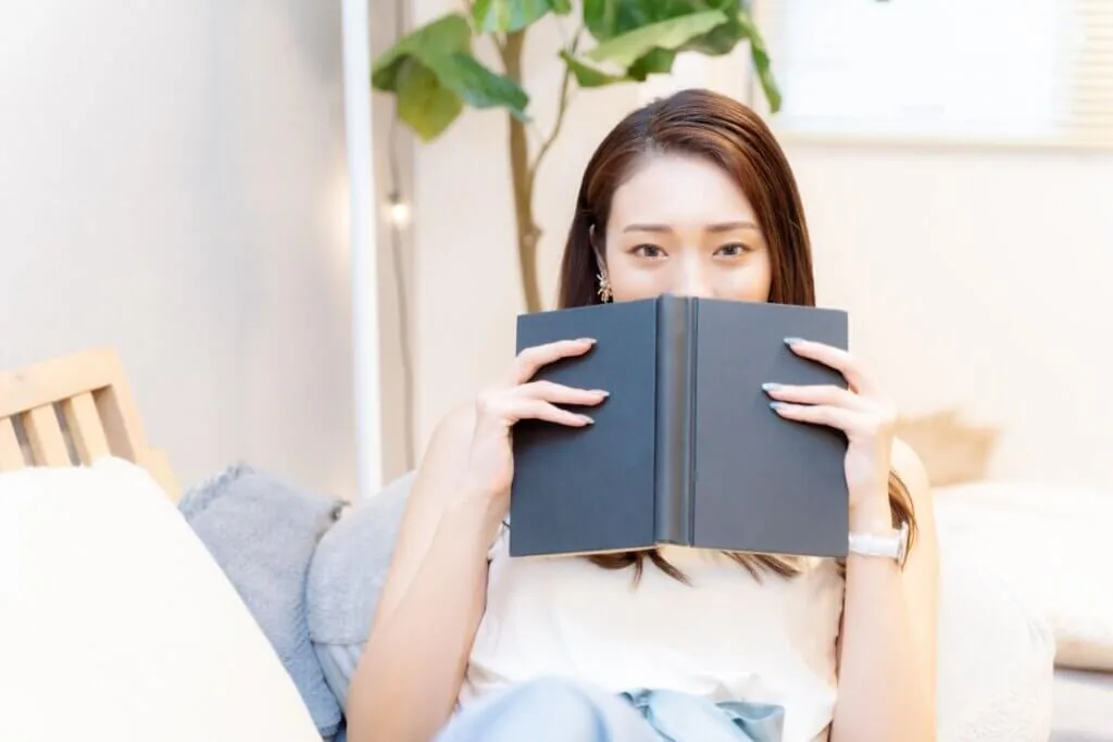本で顔を隠す女性