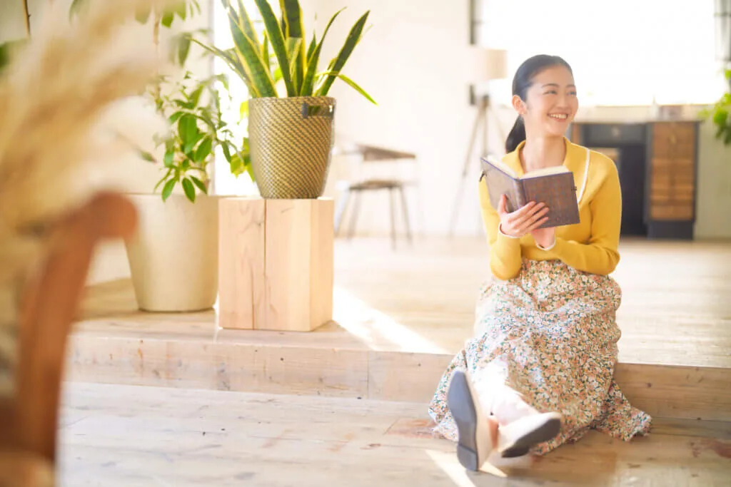 段差に座って読書をしながらよそ見をする女性