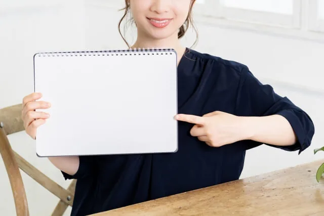 小さいスケッチブックを持つ若い女性